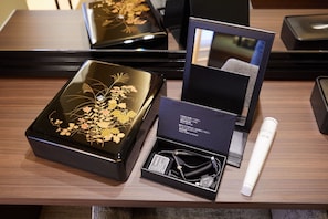 Une table en bois sur laquelle se trouvent un appareil électronique noir, un objet cylindrique blanc et une boîte noire ornée de motifs floraux.