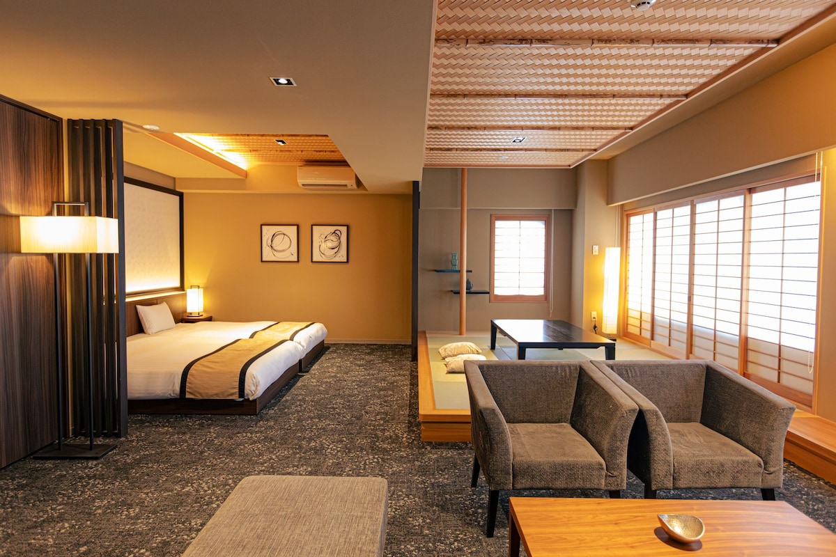 Une chambre d’hôtel avec un lit, un canapé, une table et une vue sur l’extérieur par une fenêtre.