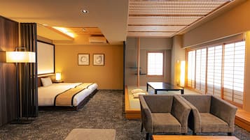 A hotel room with a bed, a sofa, a table, and a view of the outside through a window.