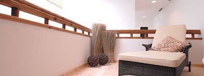 Un intérieur moderne agrémenté d’un fauteuil en osier, d’une rambarde en bois et de sphères décoratives.
