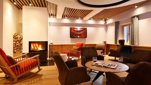 Un espace de détente moderne avec une cheminée, des sièges confortables et une grande fenêtre.