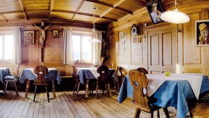 Un espace repas aux murs et au plafond en bois, avec des tables recouvertes de nappes bleues et des chaises en bois.