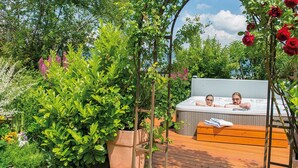 Un bain à remous entouré d’une végétation luxuriante et de plantes en fleurs.
