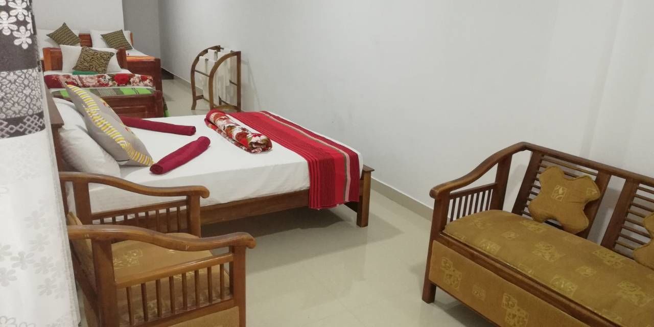 A bedroom with a bed, two wooden chairs, a wooden table, and a nightstand.