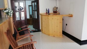 A room with a wooden bench, a small wooden counter, and a door leading to another room. - Ella Viyanga Homestay (Kumbalwela)