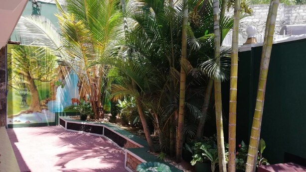 An indoor space with a stone wall, a mural, and a seating area with chairs and a table. - Ella Viyanga Homestay (Kumbalwela)