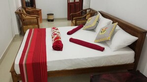 A neatly made bed with a red and white striped blanket, two pillows with decorative patterns, and a wooden headboard. - Ella Viyanga Homestay (Kumbalwela)