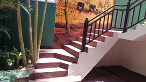 A staircase with a handrail, surrounded by plants and a mural. - Ella Viyanga Homestay (Kumbalwela)