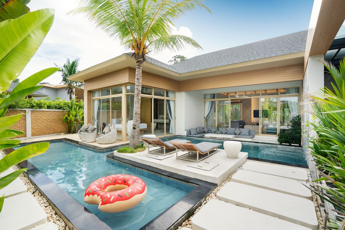 A modern house with a swimming pool, outdoor seating, and a palm tree.