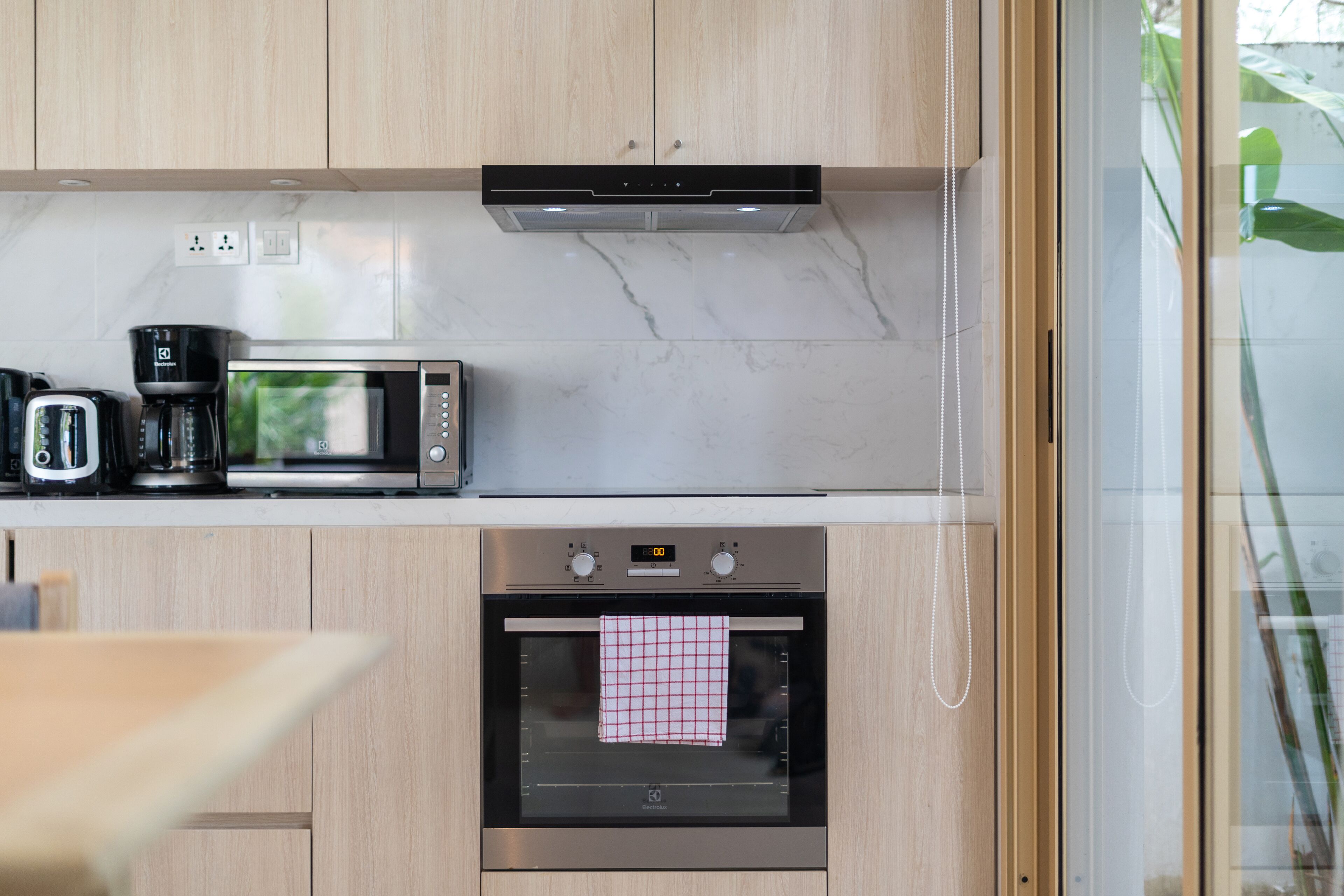 A modern kitchen with a microwave, toaster, and coffee maker on the countertop, and an oven below.