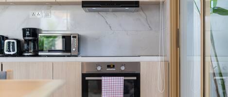 A modern kitchen with a microwave, toaster, and coffee maker on the countertop, and an oven below.