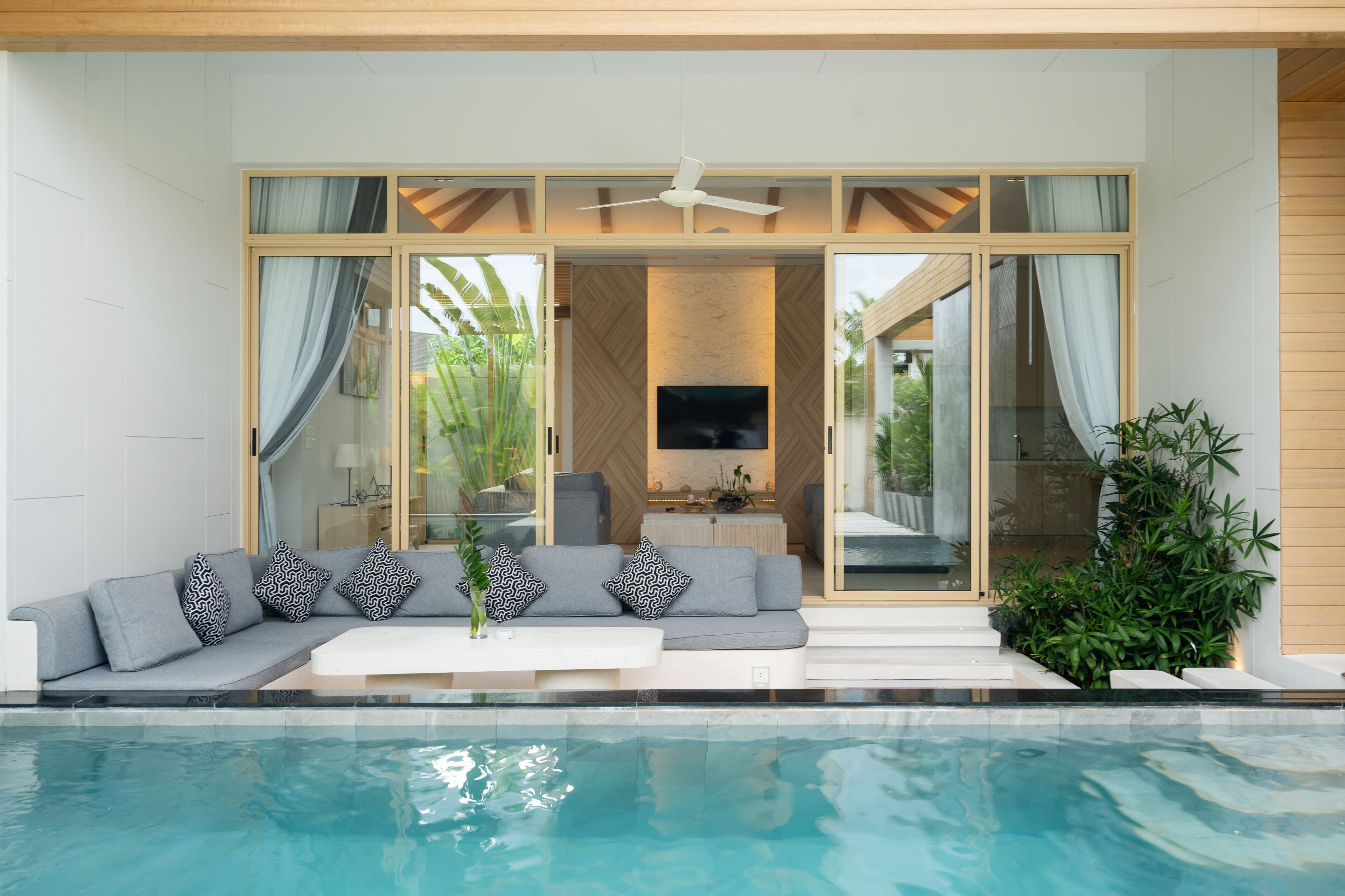 A modern living room with a sofa, TV, and a pool.