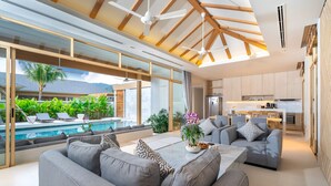 A modern living room with a pool, grey sofas, and a kitchen in the background.