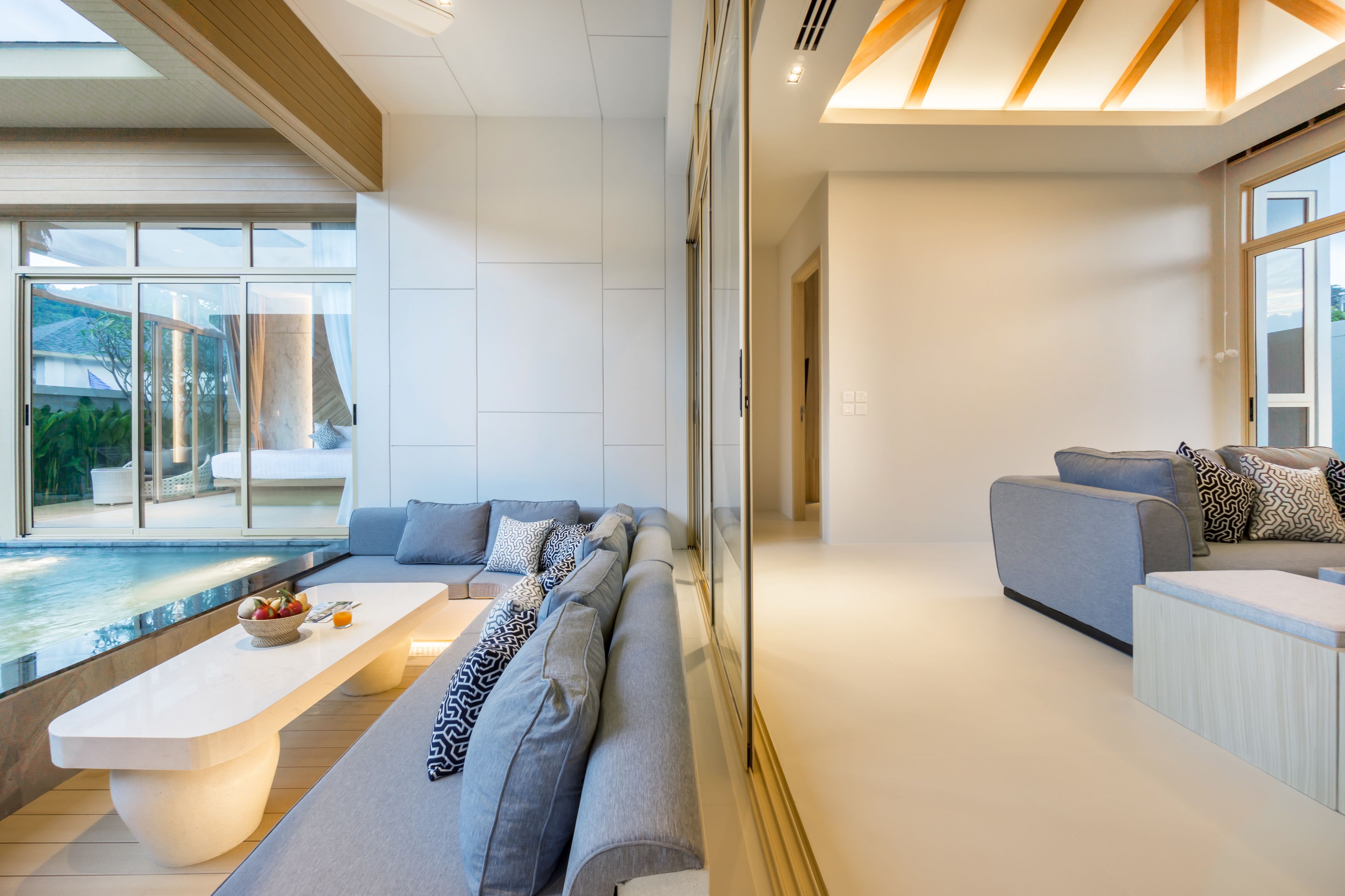 A modern living room with a pool view, a large sofa, and a dining table.
