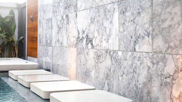 Steps lead to a wall with a marble finish, featuring a pattern of white and gray veining.