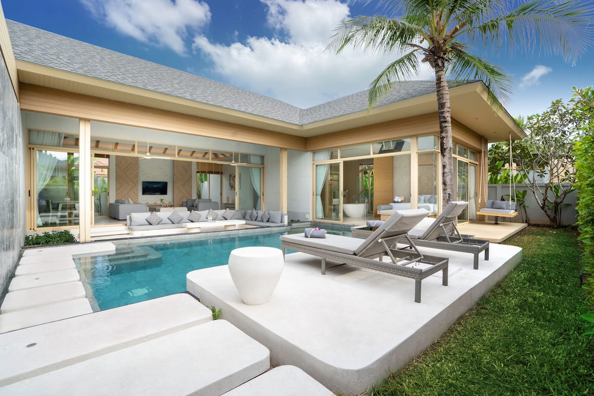 A modern house with a pool, outdoor seating, and a well-maintained lawn.