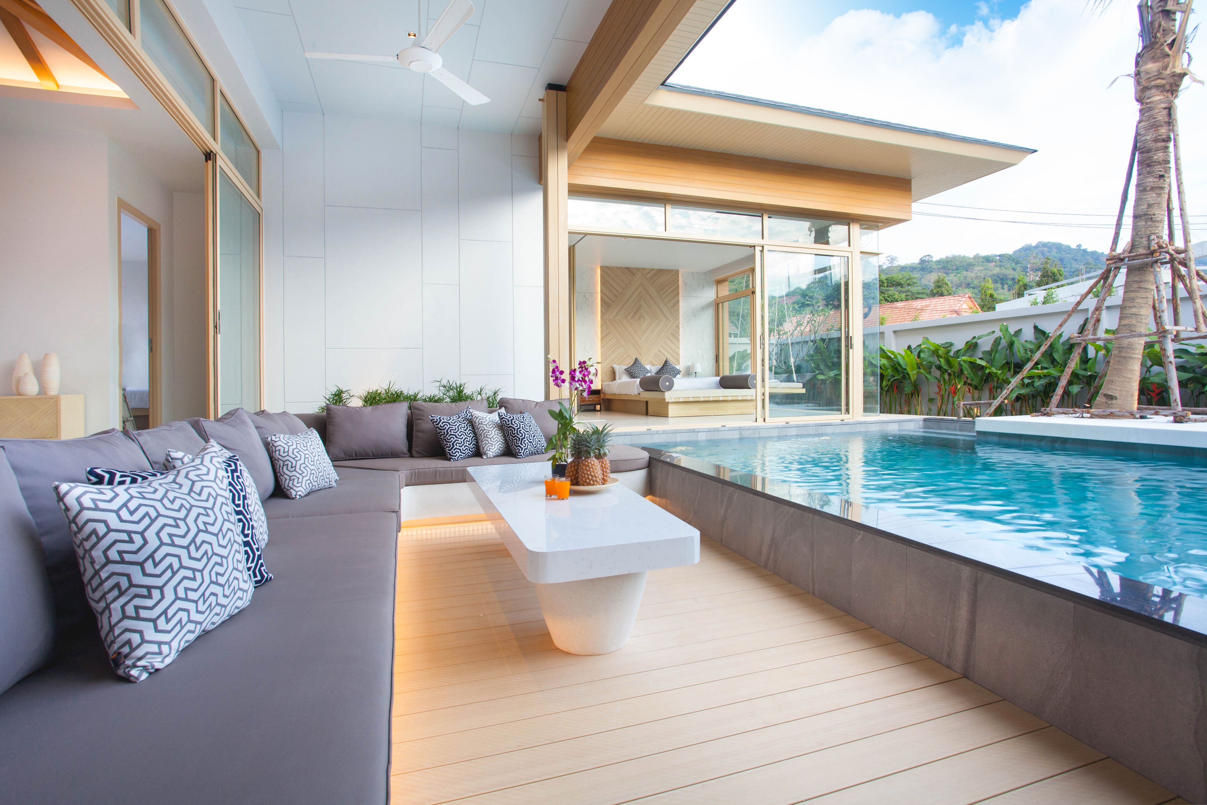 Un espace de vie moderne avec une piscine, un canapé agrémenté de coussins à motifs et une table basse décorée de divers objets.