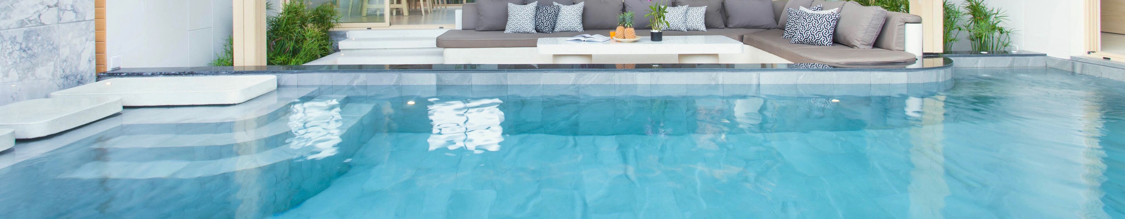 A modern outdoor pool area with a built-in seating area and steps leading into the water.