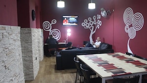 A modern conference room with a large table, black leather sofas, and a TV screen. - Summer Hostel Cádiz (Cádiz)