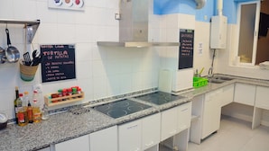 A kitchen with white cabinets, a granite countertop, and a blackboard menu listing dishes like 'Tortilla de Patatas'. - Summer Hostel Cádiz (Cádiz)