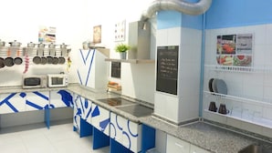 A modern kitchen with blue and white cabinetry, stainless steel appliances, and a chalkboard menu. - Summer Hostel Cádiz (Cádiz)