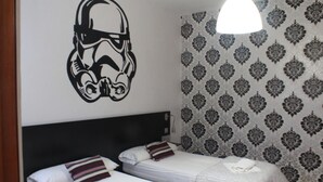 A hotel room with two beds, a headboard, patterned wallpaper, and a wall decal of a helmet. - Summer Hostel Cádiz (Cádiz)