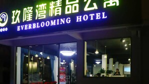 The exterior of the EverBlooming Hotel with a neon sign and large glass entrance. - Jiulongwan Boutique Apartment (Zhuhai)