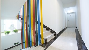 A staircase with a colorful striped barrier, a white wall, and a door at the end. - Jiulongwan Boutique Apartment (Zhuhai)