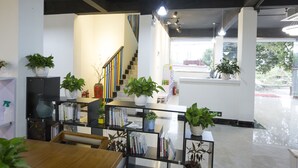 A modern interior with a staircase, bookshelves, and potted plants. - Jiulongwan Boutique Apartment (Zhuhai)