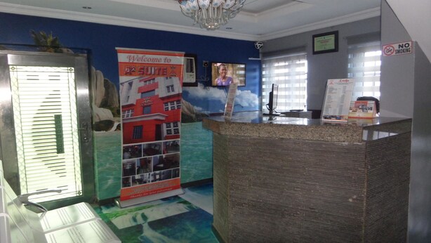 A reception area with a reception desk, a poster, a television, and a 'No Smoking' sign. - A2 Suites (Lagos)