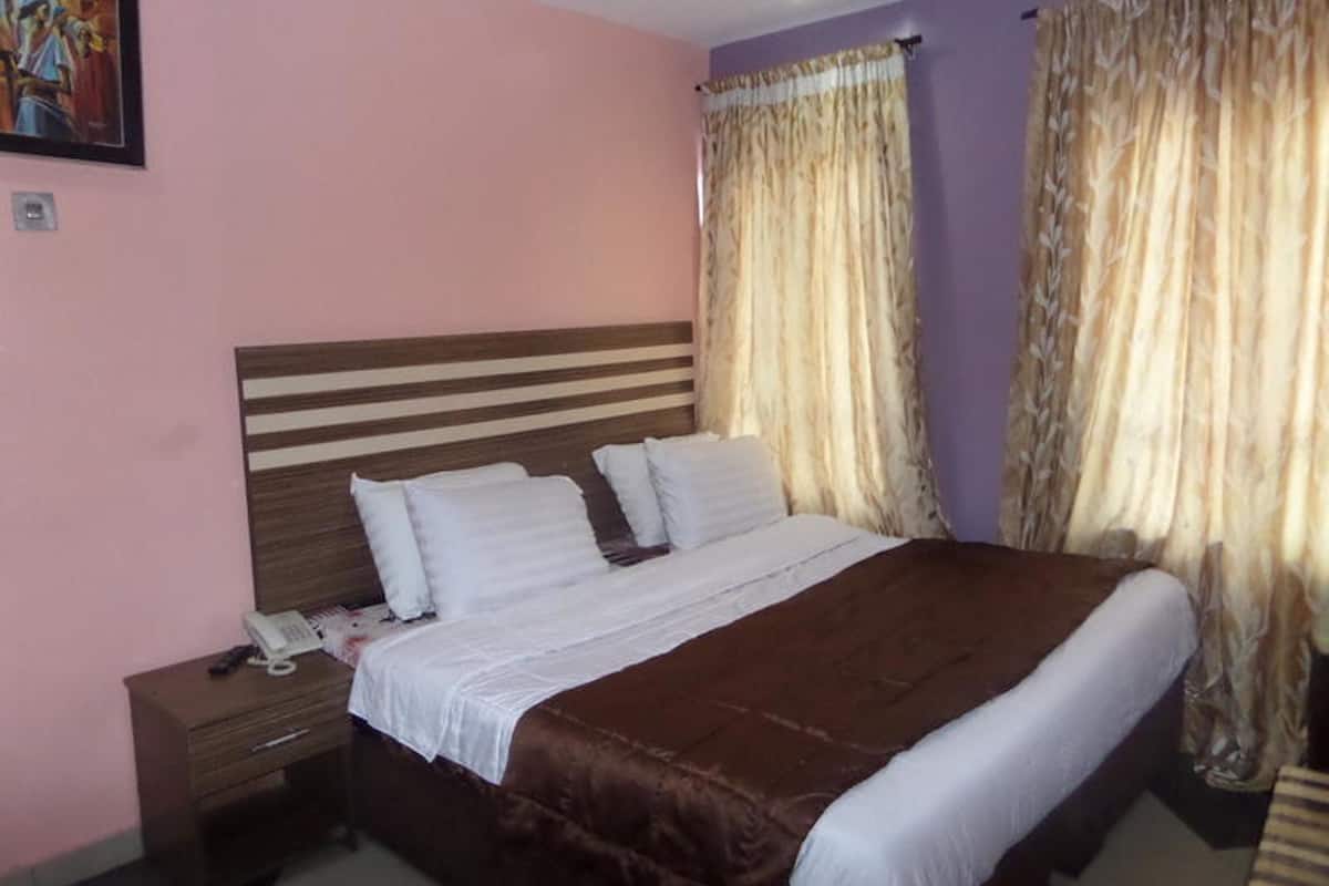 A bedroom with a bed, a nightstand, and curtains.