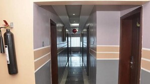 A corridor with doors on both sides, a fire extinguisher on the left, and a red object hanging from the ceiling. - A2 Suites (Lagos)