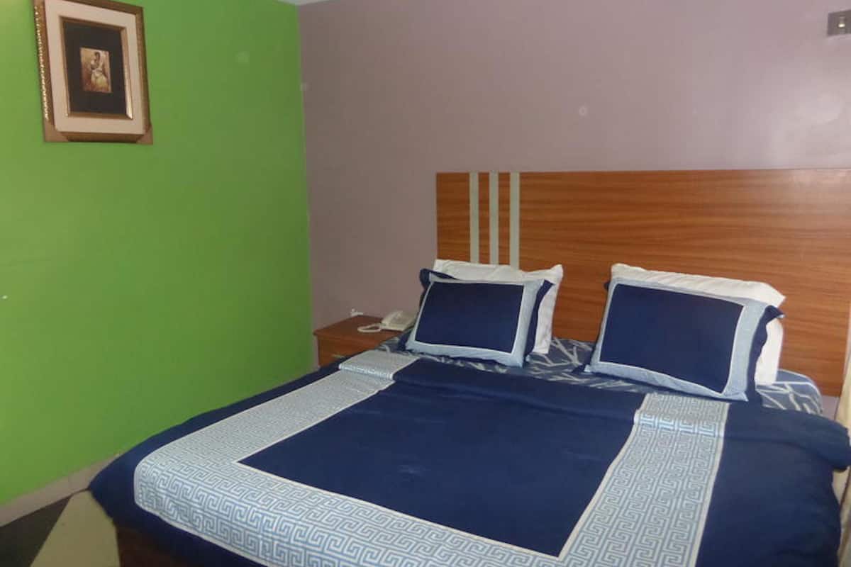 A bedroom with a bed, a bedside table, and a framed picture on the wall.