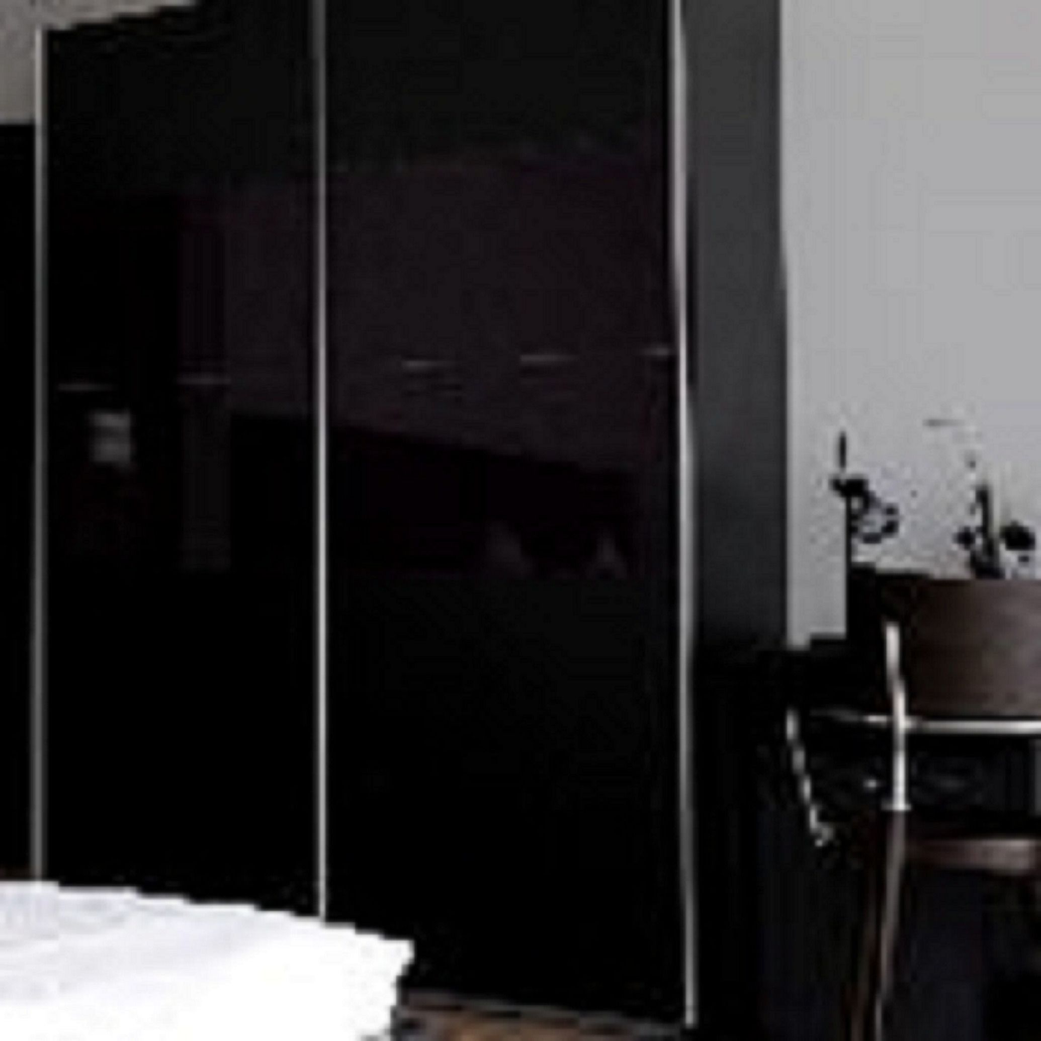 Una habitación de hotel con una cama, un armario y una mesita con una planta.
