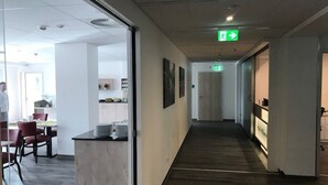 Ein modernes Interieur mit einer langen Diele, einem Empfangsbereich und einem Essbereich mit roten Stühlen.