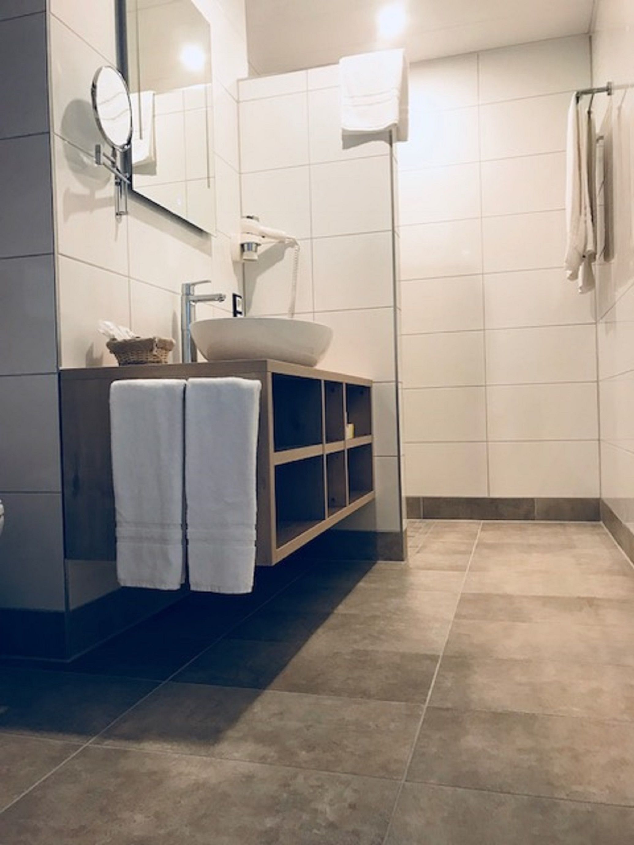 Un baño moderno con un espejo grande, un lavabo y una zona de ducha.