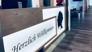 Ein Empfangsschalter mit einem Schild, das 'Herzlich Willkommen' verkündet, und einem dekorativen roten Apfel.