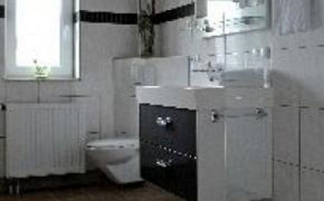 A bathroom with a toilet, sink, and cabinets.