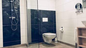A modern bathroom with a glass-enclosed shower, a toilet, and a sink with a mirror.