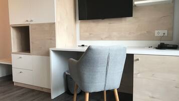 Un espace de bureau moderne comprenant un bureau, une chaise et un téléviseur à écran plat fixé au mur.