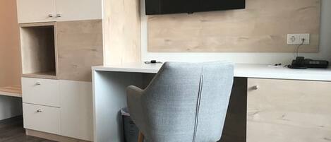 A modern office space with a desk, chair, and a mounted flat-screen TV.