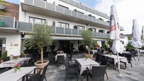Ein Straènkencafé mit Tischen und Stühlen, ein Haus mit Balkonen und Blumentöpfen.
