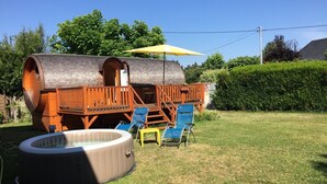 A wooden barrel-shaped structure with a deck and a hot tub in a backyard. - Gîte Amboise - Roulotte Chais Catherine (Amboise)