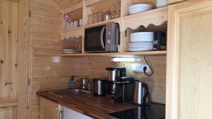 A compact kitchen with wooden cabinets, a microwave, a coffee maker, and a kettle. - Gîte Amboise - Roulotte Chais Catherine (Amboise)
