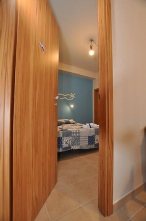 A bedroom with a bed, a blue wall, and a wooden door. - B&B La Vecchia 500 (Pignola)