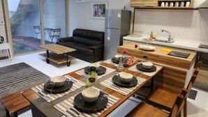 Une cuisine moderne avec un coin repas, comprenant une table en bois dressée pour un repas, un réfrigérateur et un évier.