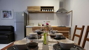 Une table à manger dressée avec des assiettes, des bols et des verres, avec une cuisine en arrière-plan.