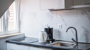 A modern kitchen with a built-in stove, a coffee maker, and a sink. - M & J Central Suites (Korcula)