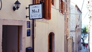 A narrow street with a building featuring a sign for 'M&J Central Suites'. - M & J Central Suites (Korcula)