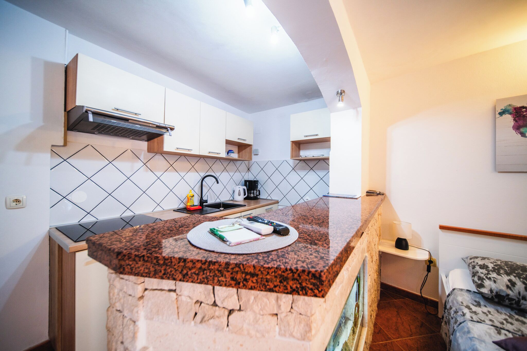 Una cocina compacta con encimera de granito, armarios blancos y una estufa integrada.
